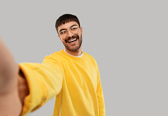 Image showing happy young man in yellow sweatshirt making selfie