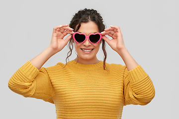 Image showing smiling young woman in heart-shaped sunglasses