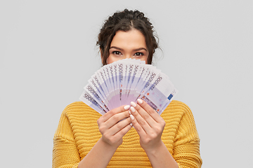 Image showing young woman covering her face with euro money