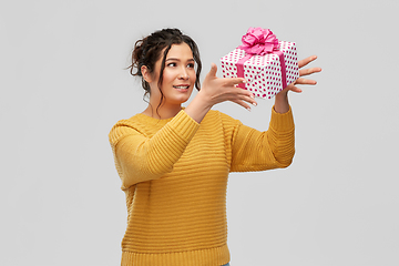 Image showing smiling young woman throwing gift box