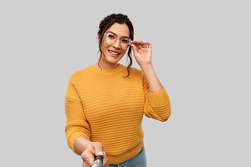 Image showing smiling woman taking picture with selfie stick