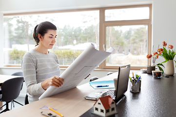 Image showing young woman with blueprint working at home office