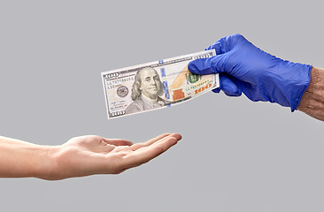 Image showing one hand in medical glove giving money to another