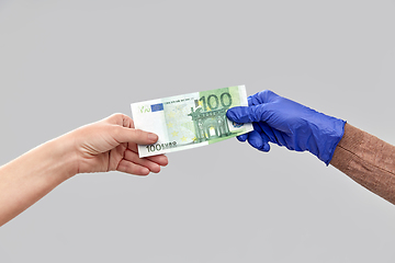 Image showing close up of hand in medical glove giving money