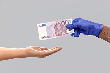 Image showing close up of hand in medical glove giving money