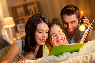 Image showing happy family reading book in bed at night at home