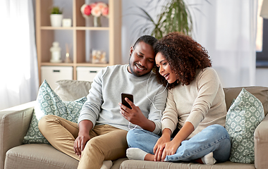 Image showing happy couple with smartphone and earphones at home