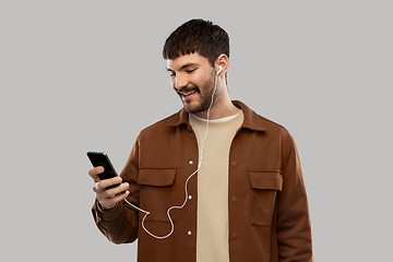 Image showing smiling young man with earphones and smartphone