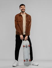 Image showing smiling young man in brown jacket with skateboard