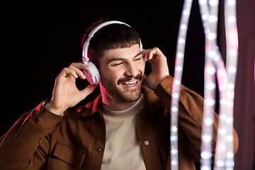 Image showing man in headphones over neon lights of night club