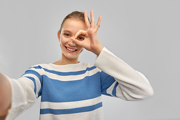 Image showing smiling teenage girl in pullover taking selfie