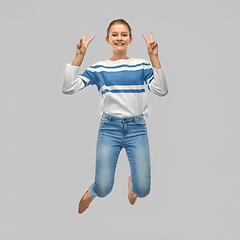 Image showing smiling teenage girl jumping and showing peace