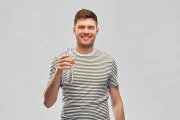 Image showing happy smiling man holding water in glass bottle