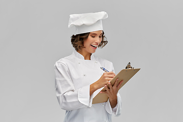 Image showing smiling female chef in toque with clipboard