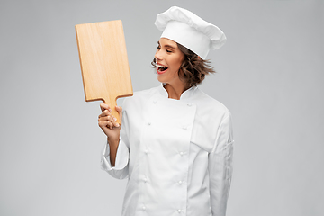 Image showing smiling female chef in toque with cutting board