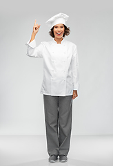 Image showing smiling female chef in toque pointing finger up