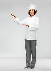 Image showing smiling female chef holding something on hand