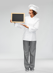 Image showing smiling female chef holding black chalkboard