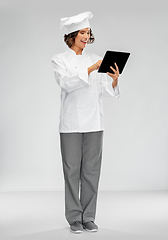 Image showing smiling female chef in toque with tablet computer