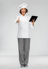 Image showing smiling female chef in toque with tablet computer