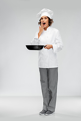 Image showing surprised female chef in toque with frying pan