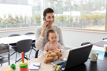 Image showing mother with baby working on laptop at home office