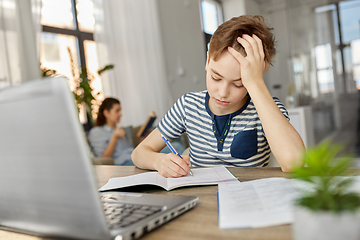 Image showing student boy with book writing to notebook at home