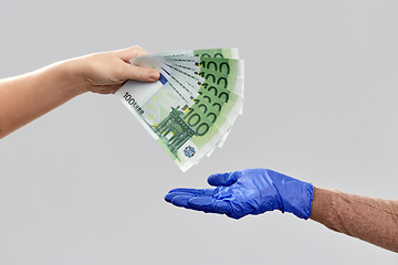 Image showing close up of hand in medical glove giving money