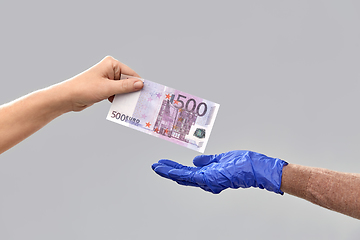 Image showing close up of hand in medical glove giving money