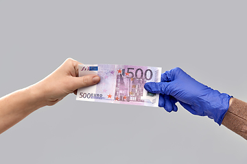 Image showing close up of hand in medical glove giving money