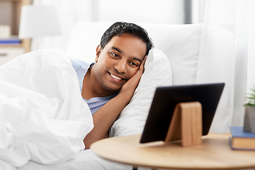 Image showing happy indian man with tablet pc in bed at home