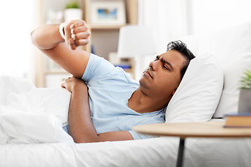 Image showing indian man in bed looking at smart watch at home