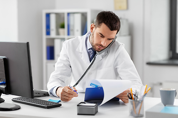 Image showing male doctor calling on desk phone at hospital