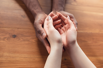 Image showing Close up of african-american male and caucasian female hands holding