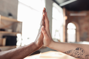 Image showing Close up of african-american male and caucasian female hands, working in office