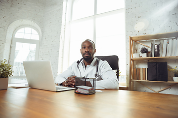 Image showing African-american doctor consulting for patient, working in cabinet