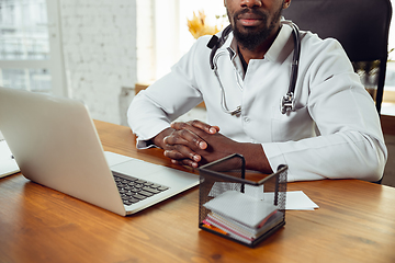 Image showing African-american doctor consulting for patient, working in cabinet