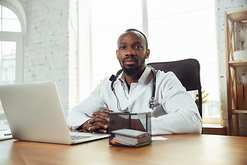 Image showing African-american doctor consulting for patient, working in cabinet