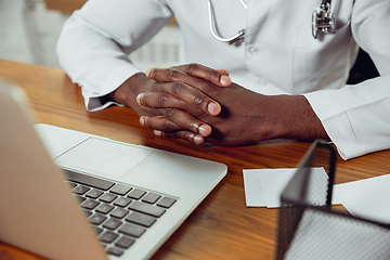 Image showing African-american doctor consulting for patient, working in cabinet, close up