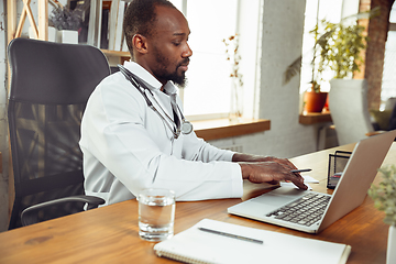 Image showing African-american doctor consulting for patient, working in cabinet