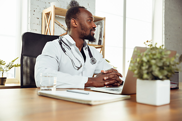 Image showing African-american doctor consulting for patient, working in cabinet