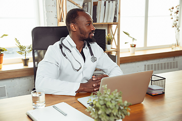 Image showing African-american doctor consulting for patient, working in cabinet