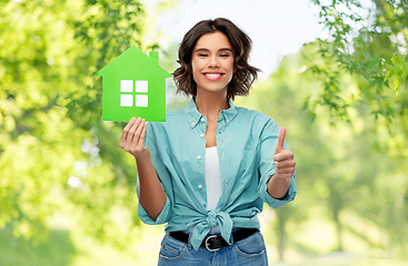 Image showing smiling woman with green house showing thumbs up