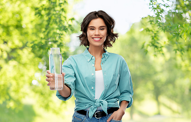 Image showing smiling young woman holding water in glass bottle