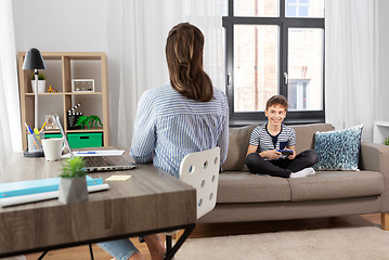 Image showing smiling boy with gamepad talking to mother at home