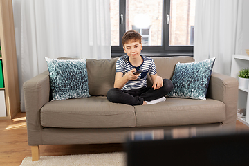 Image showing bored boy with remote control watching tv at home