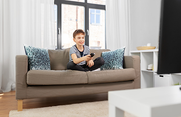 Image showing happy boy with remote control watching tv at home