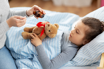 Image showing mother pouring cough syrup for sick daughter