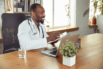 Image showing African-american doctor consulting for patient, working in cabinet, close up