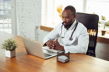 Image showing African-american doctor consulting for patient, working in cabinet, close up